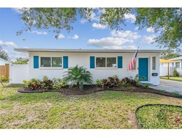 Charming single-story home features bright blue shutters and a neatly landscaped front yard with an American flag at 1529 Essex N Dr, St Petersburg, FL 33710