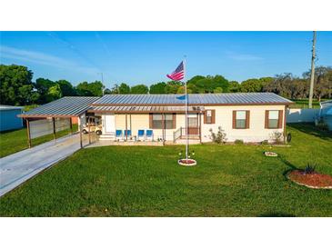 Charming single-story home boasts a well-manicured lawn, covered carport, and a welcoming porch with blue seating at 5409 Antigua Dr, Zephyrhills, FL 33541