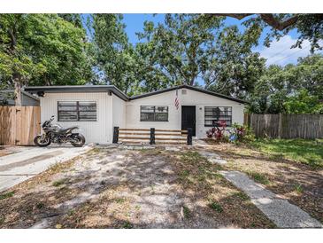 Charming single-story home with white exterior, black trim, mature trees, and motorcycle parked near driveway at 5801 92Nd N Ave, Pinellas Park, FL 33782