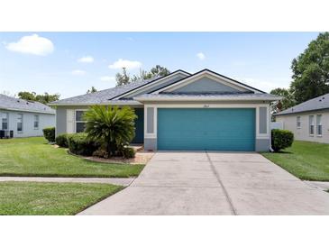 Charming single-story home featuring a vibrant blue garage door and well-manicured landscaping at 11845 Autumn Creek Dr, Riverview, FL 33569