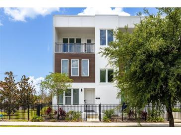 Modern three-story townhome featuring white exterior, dark trim, and a black metal fence at 121 E Warren Ave # 4, Tampa, FL 33602