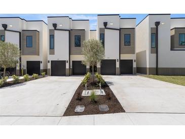 Modern townhome exterior featuring a clean facade, dark garage doors, and a landscaped front at 218 Hesperides N St, Tampa, FL 33609