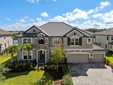 Stately two-story home featuring a stone facade, manicured lawn, paver driveway and a three-car garage at 33255 Kateland Dr, Wesley Chapel, FL 33545