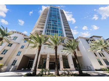 Stunning high-rise building with lush landscaping and tall palm trees against a blue sky at 450 Knights Run Ave # 104, Tampa, FL 33602