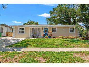 Charming single-story home features a well-manicured lawn, blue door, and inviting curb appeal at 4701 W Wyoming Ave, Tampa, FL 33616