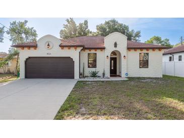 Charming home featuring a brown two-car garage and stucco facade with a beautiful lawn at 8523 N Newport Ave, Tampa, FL 33604