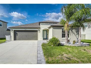 Charming single-story home featuring a gray two-car garage, well-manicured lawn, and stylish landscaping at 8812 Parsons Hill Blvd, Wesley Chapel, FL 33545