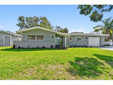 Charming one-story home with a well-manicured lawn, brick accents, and a freshly painted exterior at 94 Nicholas Dr, Dunedin, FL 34698
