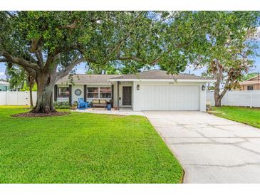 Charming single-story home with an attached garage, lush green lawn and mature shade tree at 2334 Tropical Shores Se Dr, St Petersburg, FL 33705