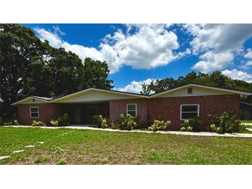 Charming single-story red brick home with a covered porch and beautiful landscaping at 3419 Pearson Rd, Valrico, FL 33596