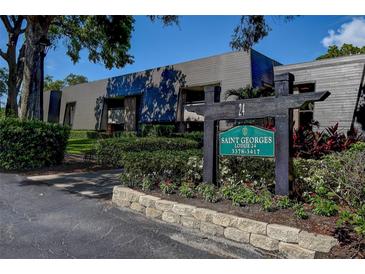 Attractive condo complex exterior with lush landscaping and a sign at 36750 Us 19 N # 24-213, Palm Harbor, FL 34684