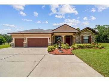 Inviting single-story home with a well-manicured lawn, mature landscaping, and a three-car garage at 4608 Scott Rd, Lutz, FL 33558