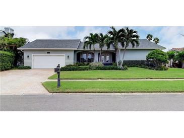 Charming single-story home boasts lush landscaping, a paver driveway, and welcoming double door entry at 731 Island Way, Clearwater, FL 33767