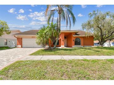 Charming single-story home with a well-manicured lawn, brick driveway and lush palm trees at 8601 Chadwick Dr, Tampa, FL 33635