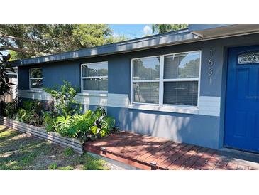 Charming home featuring a well-manicured front yard and inviting blue exterior with a quaint front porch at 1631 St Mary Dr, Dunedin, FL 34698
