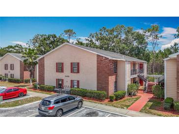 Exterior view of an apartment with red brick accents, well-maintained landscaping, and parking area at 21032 Voyager Blvd # 8, Land O Lakes, FL 34638