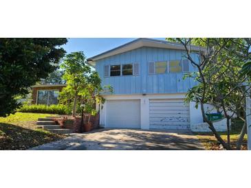 Two-story home featuring blue siding, white garage doors, and steps leading to the front entrance at 3717 Mckay Creek Dr, Largo, FL 33770