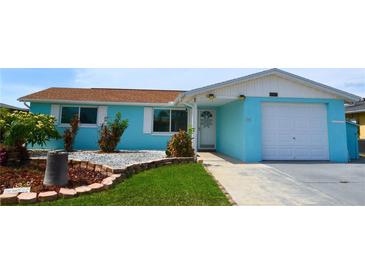 Charming single-story home with blue exterior, well-maintained landscaping, and an attached garage at 3839 Star Island Dr, Holiday, FL 34691