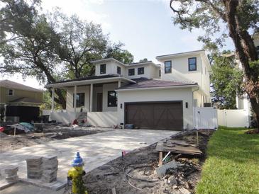 New home with a brick driveway, brown garage door, white exterior, and a covered front porch at 4612 W Tennyson Ave, Tampa, FL 33629