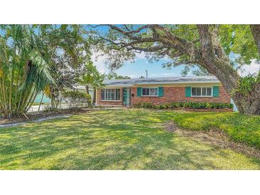 Charming brick home featuring well-maintained lawn, mature trees, and bright, eye-catching shutters at 4915 Chariton Ave, Tampa, FL 33603
