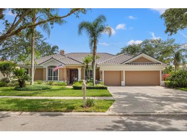 Beautiful single-story home with lush landscaping, a tile roof, and a spacious two-car garage on a sunny day at 9348 Deer Creek Dr, Tampa, FL 33647