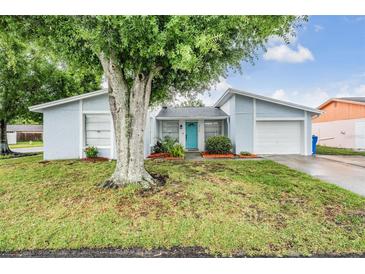 Charming single Gathering home featuring a vibrant blue front door, attached garage, and mature landscaping at 10110 Pepperidge Ct, Tampa, FL 33615