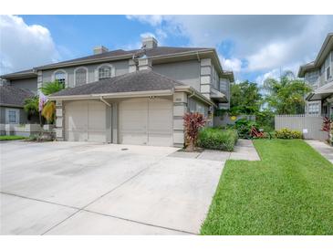 Exterior view of the townhome with a two-car garage and a well-maintained lawn at 14116 Trouville Dr, Tampa, FL 33624