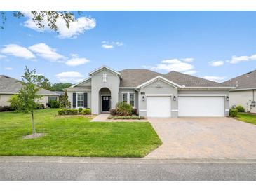 Charming single-story home with a well-manicured lawn and a brick driveway leading to a two-car garage at 19819 Tattnall Way, Brooksville, FL 34601
