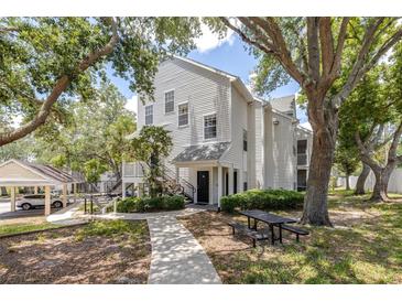 Charming two-story condo featuring a picnic table, lush landscaping, and covered parking at 3301 Haviland Ct # 203, Palm Harbor, FL 34684