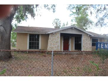 Charming single-story home with a stone facade and a red front door, set behind a chain link fence at 3513 Beechwood Blvd, Tampa, FL 33619