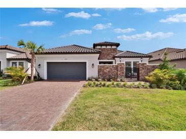 Charming single-Gathering home featuring stone accents, tile roof, well-manicured lawn and brick driveway at 4795 Freccia Loop, Wesley Chapel, FL 33543