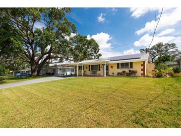 Charming single-story home with a lush green lawn, covered front porch, and carport with solar panels at 5675 Lown N St, St Petersburg, FL 33714