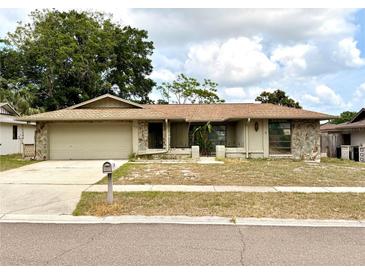 Charming single-story home featuring stone accents, a two-car garage, and a well-maintained front yard at 613 Sandy Hollow Rd, Tarpon Springs, FL 34689