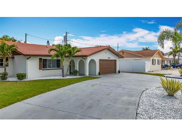 Charming single-story home with a red tile roof, arched entryway, and well-manicured lawn with palm trees at 7125 S Shore S Dr, St Petersburg, FL 33707