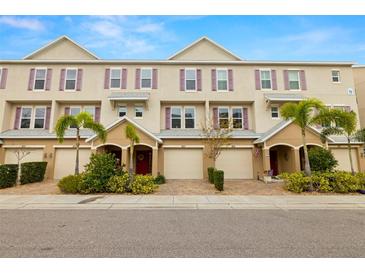 Attractive exterior townhome row with neutral paint, purple shutters, paved driveways and lush landscaping at 807 Callista Cay Loop, Tarpon Springs, FL 34689