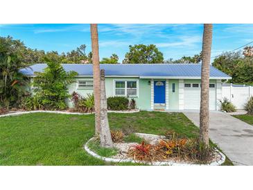 Charming single-story home with a well-manicured lawn and a bright blue front door beneath a new metal roof at 9929 Bay Dr, Gibsonton, FL 33534