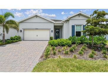 Charming single-story home with well-manicured landscaping, a paver driveway, and a bright, welcoming facade at 10036 Beachwalk Dr, Englewood, FL 34223