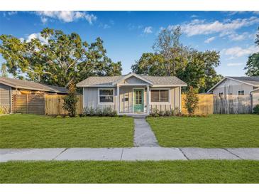 Charming single-story home with a well-manicured lawn, mature trees and a tidy walkway to the front door at 1052 55Th N Ave, St Petersburg, FL 33703