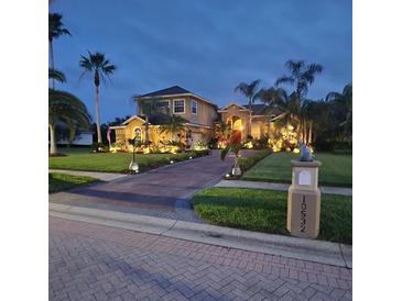 Stunning home at dusk featuring lush landscaping, elegant lighting, and a paver driveway at 10532 Cory Lake Dr, Tampa, FL 33647
