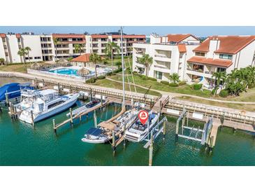 An aerial view of waterfront condos with private boat docks, a pool, and lush landscaping at 120 1St E St # 109, Tierra Verde, FL 33715