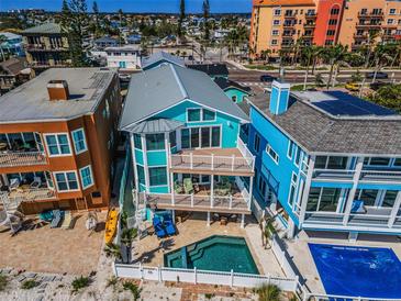 Stunning three-story beachfront home with balconies, a pool, and coastal charm at 13303 Gulf Ln, Madeira Beach, FL 33708