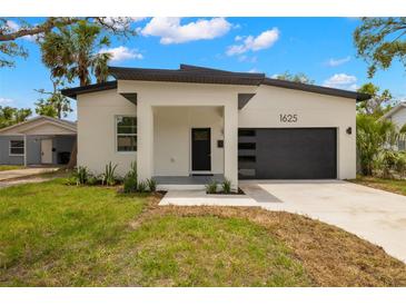 Modern single-Gathering home featuring a sleek black garage door, white facade, and minimalist landscaping at 1625 39Th S St, St Petersburg, FL 33711