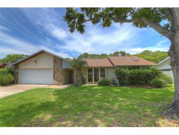 Charming single-story home featuring a well-manicured lawn and a stone facade accent, offering a welcoming curb appeal at 313 Oak Crest Dr, Safety Harbor, FL 34695