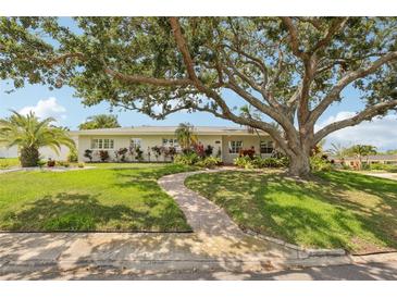 Charming single-story home featuring a beautiful brick walkway, lush lawn, mature tree, and manicured landscaping at 3966 High Bluff Dr, Largo, FL 33770