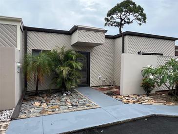 Charming townhome featuring a unique tree overhanging, stone walkway, and neutral paint scheme at 4309 Cedar Grove St, Holiday, FL 34691