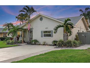 Charming single-story home featuring a well-manicured lawn, palm trees, and a welcoming facade at 6521 69Th N Ave, Pinellas Park, FL 33781