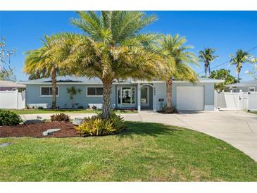 Charming single story home with mature palm trees, well manicured lawn, and updated curb appeal on a sunny day at 9485 Treasure Ne Ln, St Petersburg, FL 33702