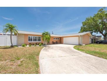 Charming single-story home featuring a spacious driveway, two-car garage, and tropical landscaping at 9591 Commodore Dr, Seminole, FL 33776
