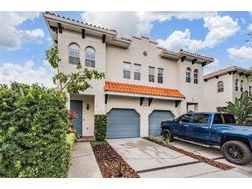 Charming two-story home showcasing blue garages and a terracotta tile roof with lush landscaping at 102 S Moody Ave # 1, Tampa, FL 33609