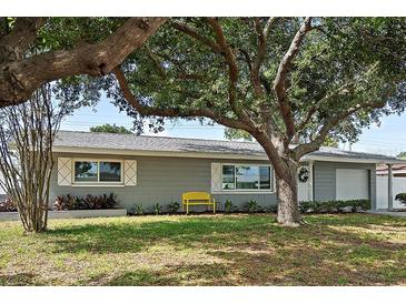 Charming single-story home with mature trees, green lawn, and a cheerful yellow bench out front at 11720 80Th Ave, Seminole, FL 33772